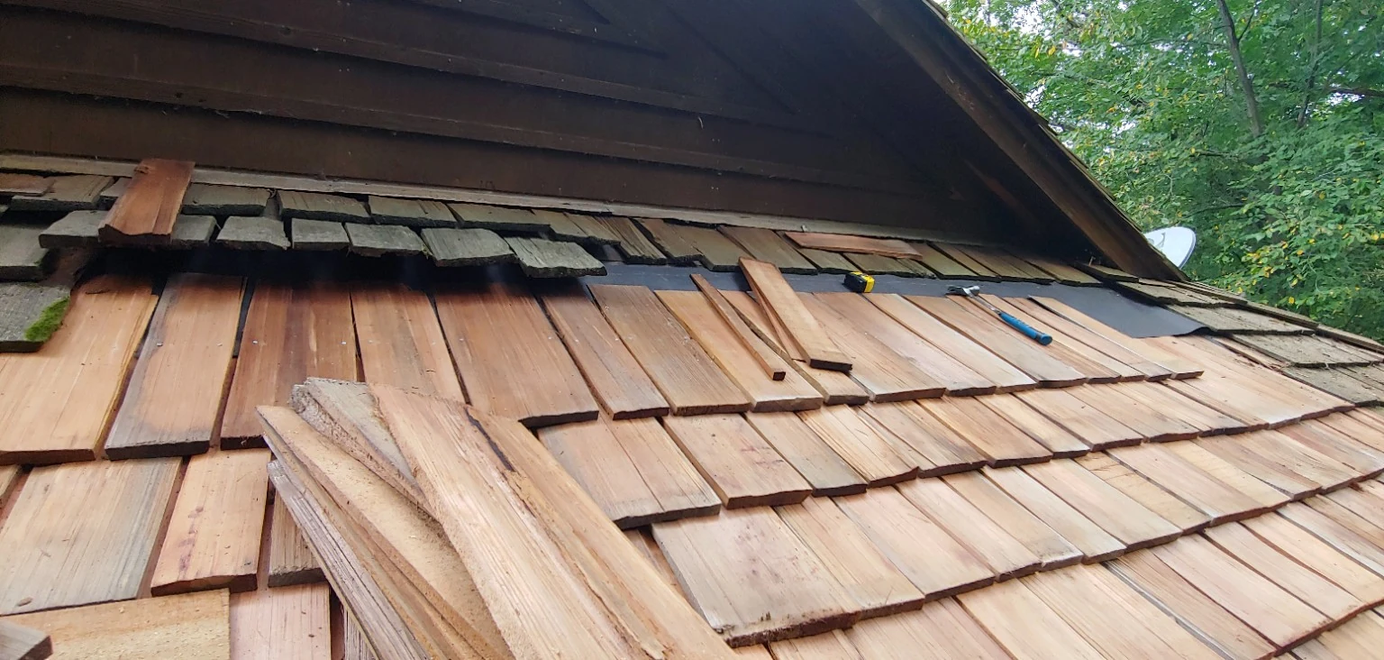 Individual cedar shakes being replaced during roof repair