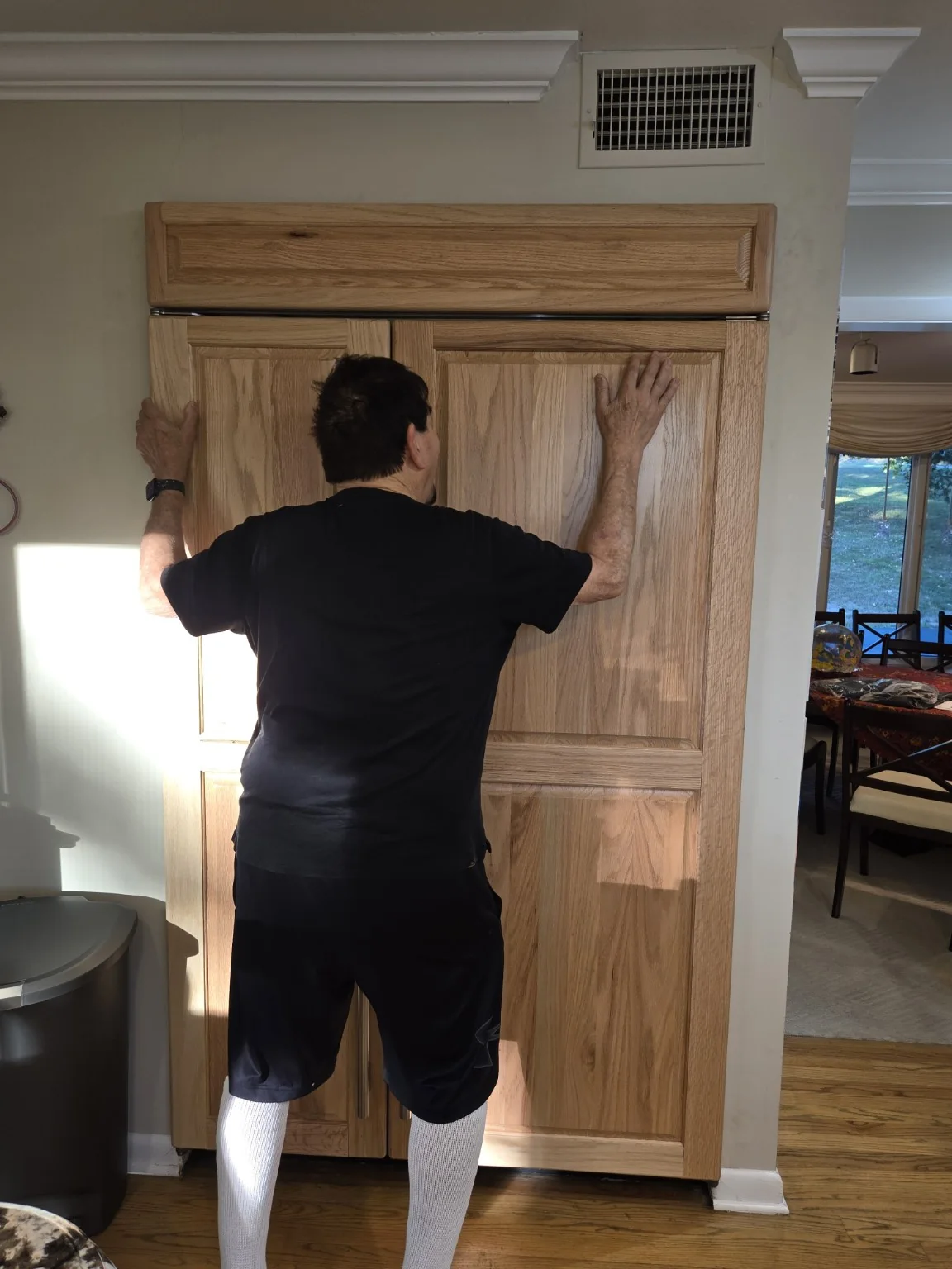 Happy homeowner hugging the completed Sub-Zero refrigerator with custom oak panels